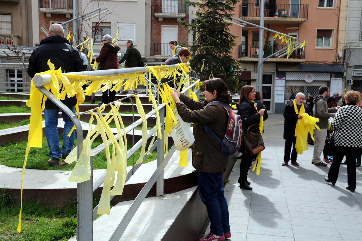 Una noia penja llaços grocs a una tanca de la plaça Ricard Vinyes de Lleida