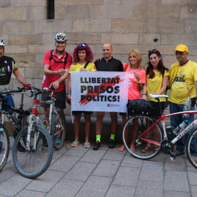 Els tres ciclistes, amb altres persones que els acompanyaven, mostrant una pancarta reclamant l'alliberament dels presos, abans d'iniciar la pedalada a la plaça Paeria de Lleida