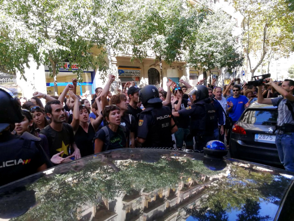 La policia espanyola envoltant la seu de la CUP, mentre simpatitzants criden en contra de l'actuació i en favor de l'1-O, el 20 de setembre de 2017