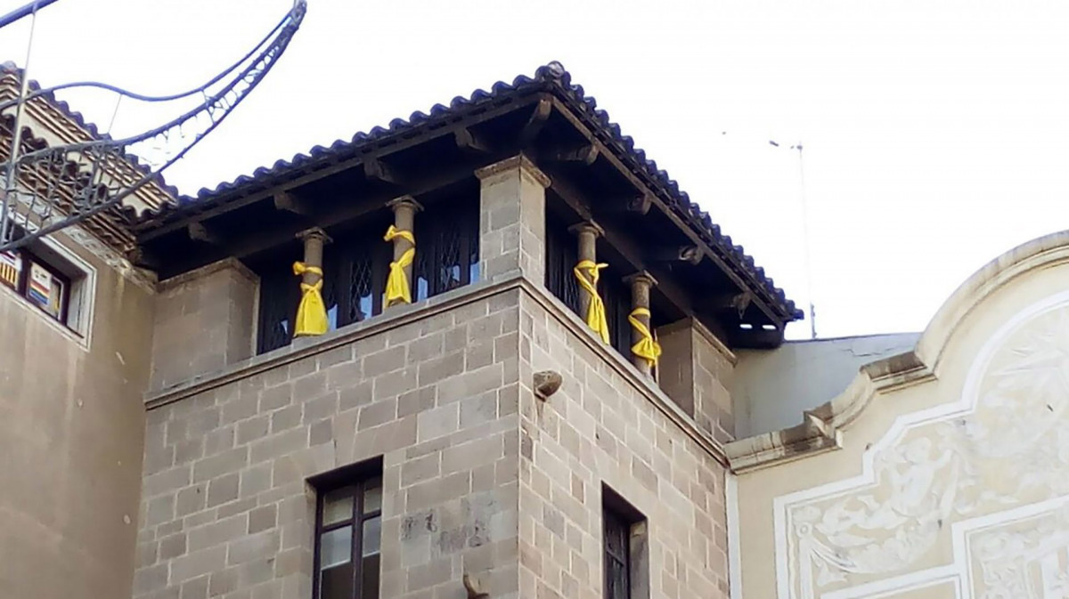 Pla curt on es poden veure quatre llaços grocs lligats al capdamunt de la façana de la Paeria a l'alçada del despatx de la Crida-CUP/ Crida per Lleida