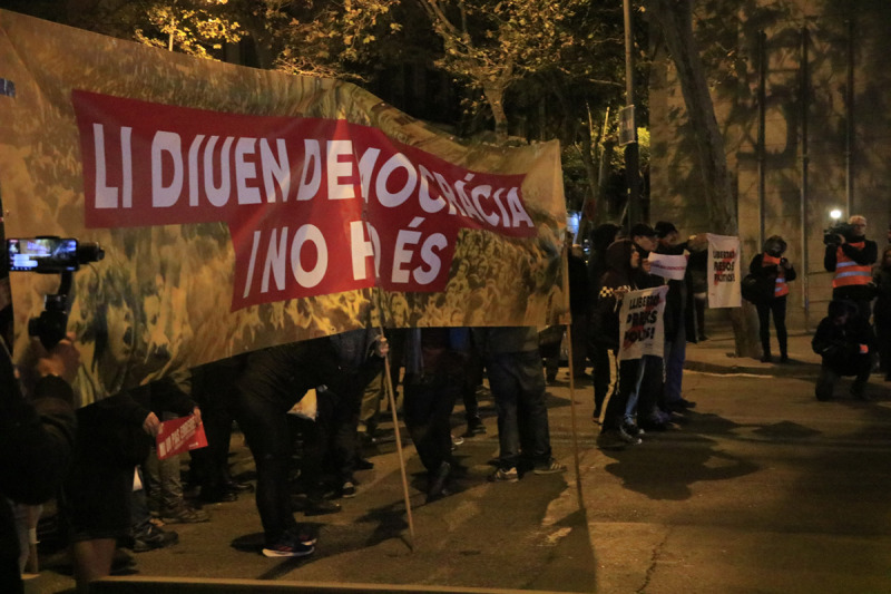 Pancarta amb el lema 'Li diuen democràcia i no ho és' en la protesta de CDR al míting final de campanya de Pedro Sánchez a Barcelona